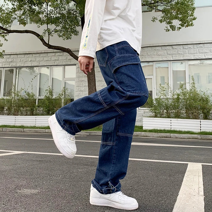 Man wearing stylish baggy jeans men's cargo pants with patchwork design and white sneakers, standing outdoors.