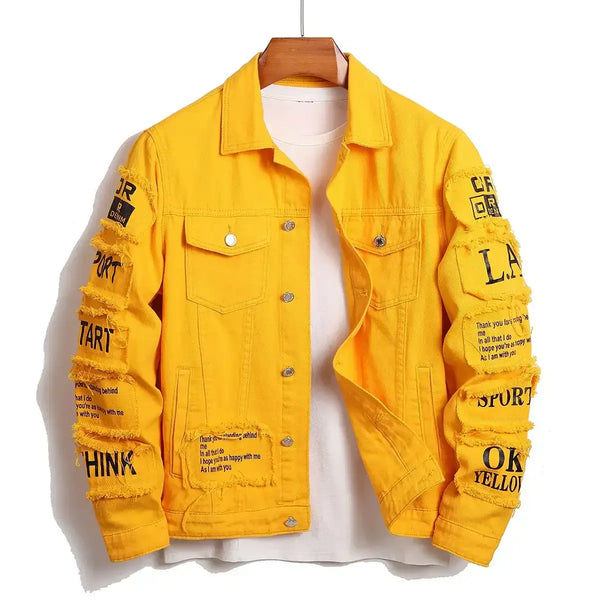 Yellow denim jacket with black text and patches on sleeves, featuring a collar and buttoned front, hung on wooden hanger.