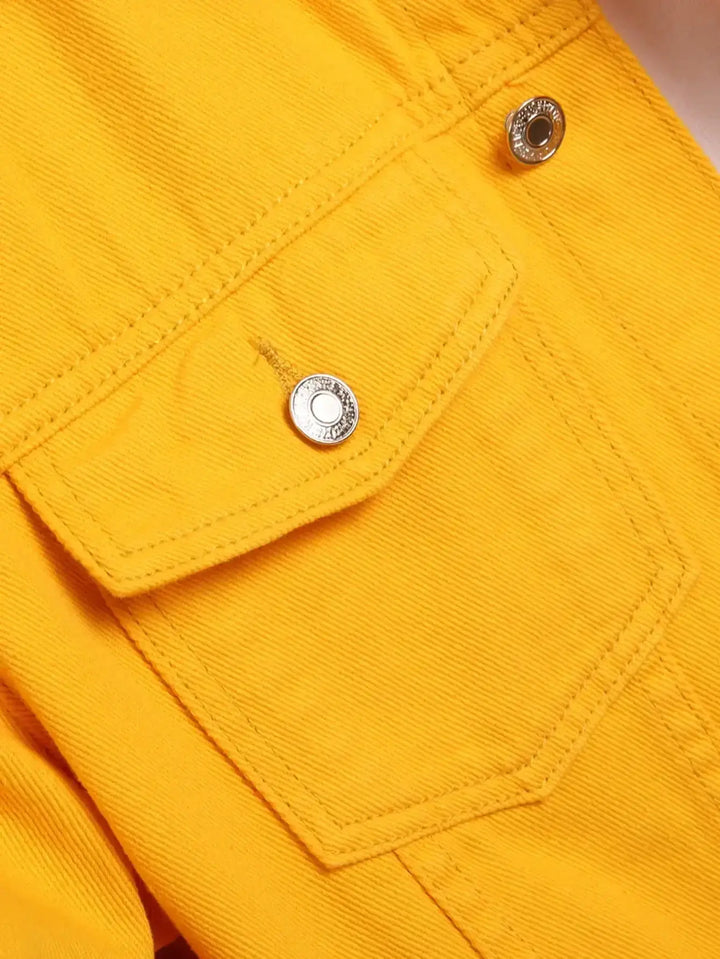 Close-up of a yellow denim jacket pocket with silver button detailing, showcasing vibrant fabric texture.