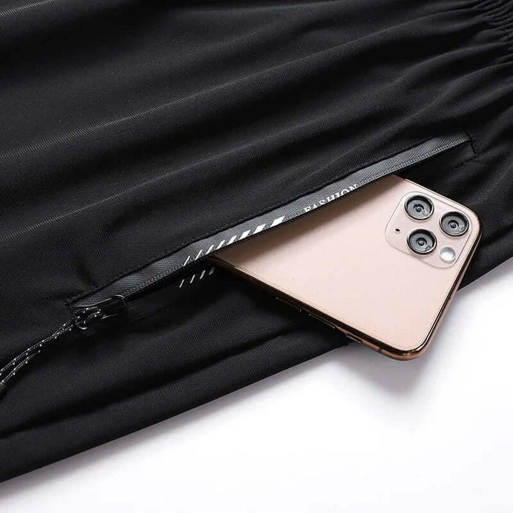 Black sweatpants with zip pocket holding a smartphone for convenient storage.