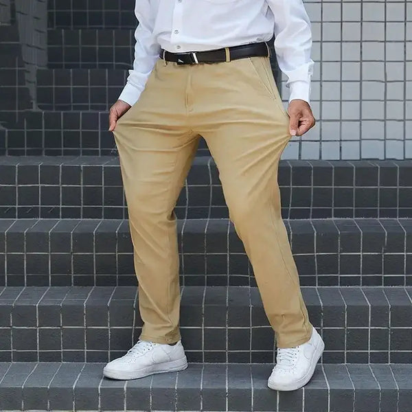 Man wearing relaxed fit stretch pants in beige, showcasing comfort and style, paired with white sneakers and a dress shirt.