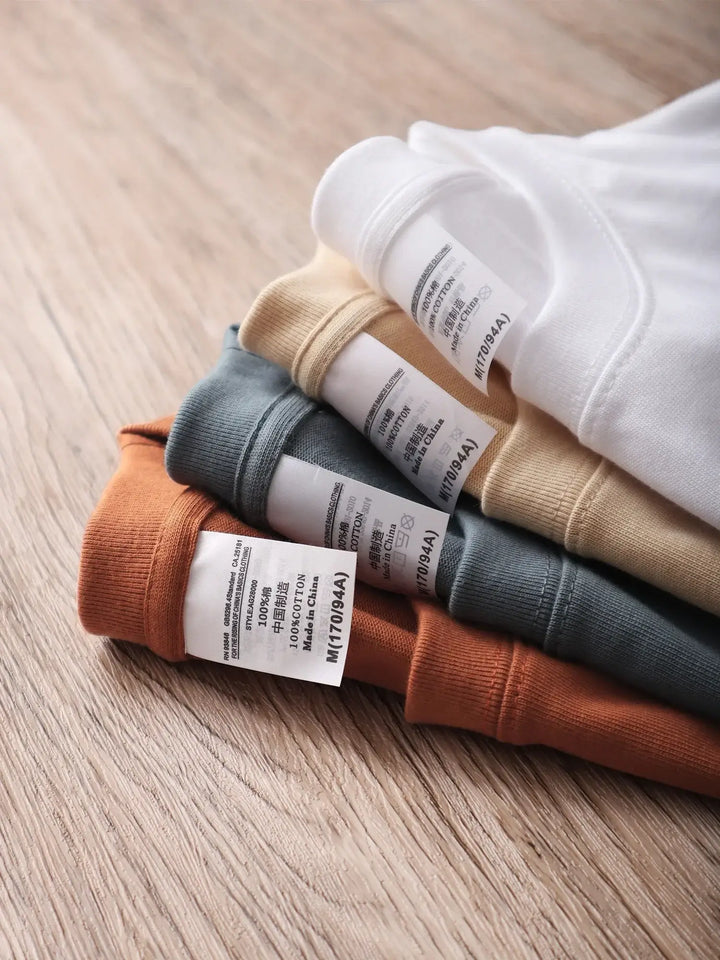 Oversized unisex cotton t-shirts in various colors laid on wooden surface, showcasing quality and comfort.